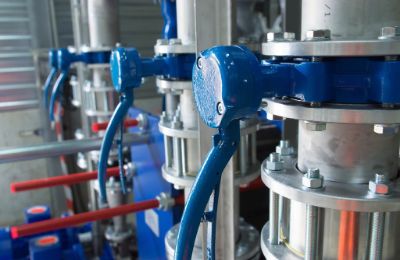 Blue actuated valves and flanged pipework on a compact process skid.